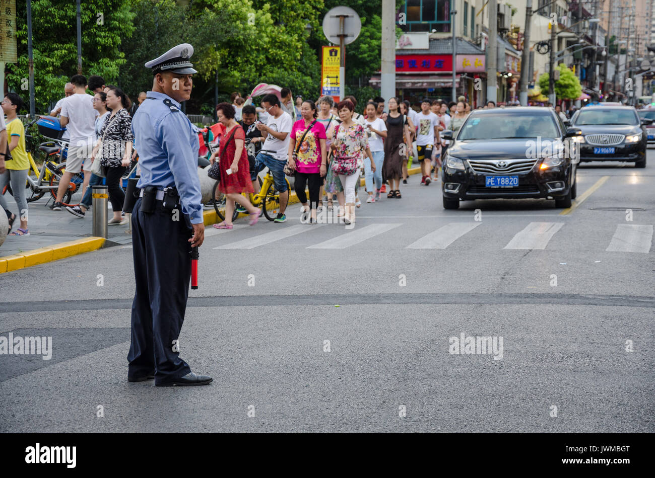 A police officer in Shanghai stands in the road to direct traffic. Stock Photo