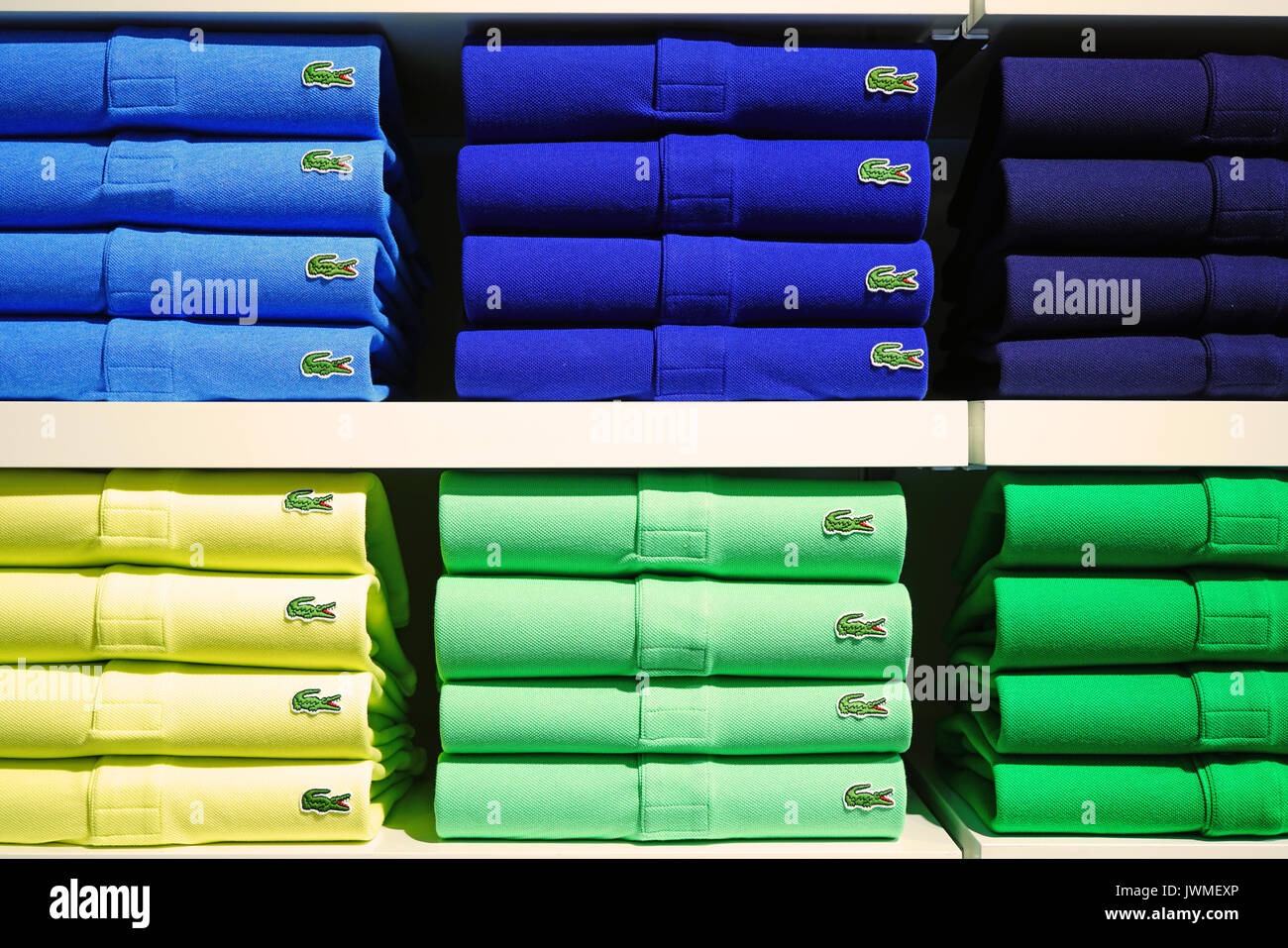 Piles of colorful Lacoste polo shirts on store shelves. Lacoste is