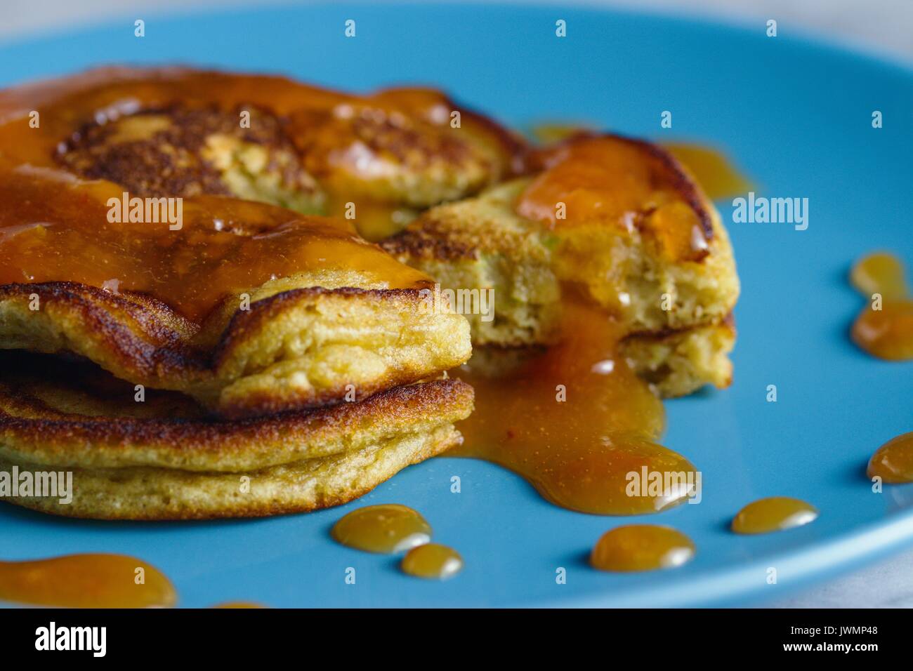 Homemade gluten free pancakes with peach jam served on sky blue plate. Close up shot Stock Photo