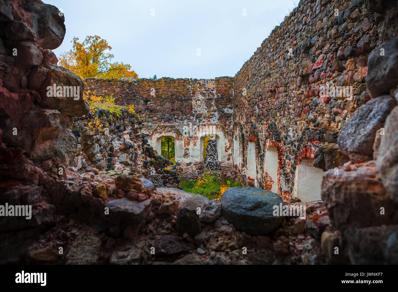 Medieval stone granite castle ruins at fall time. Autumn foliage. Rauna