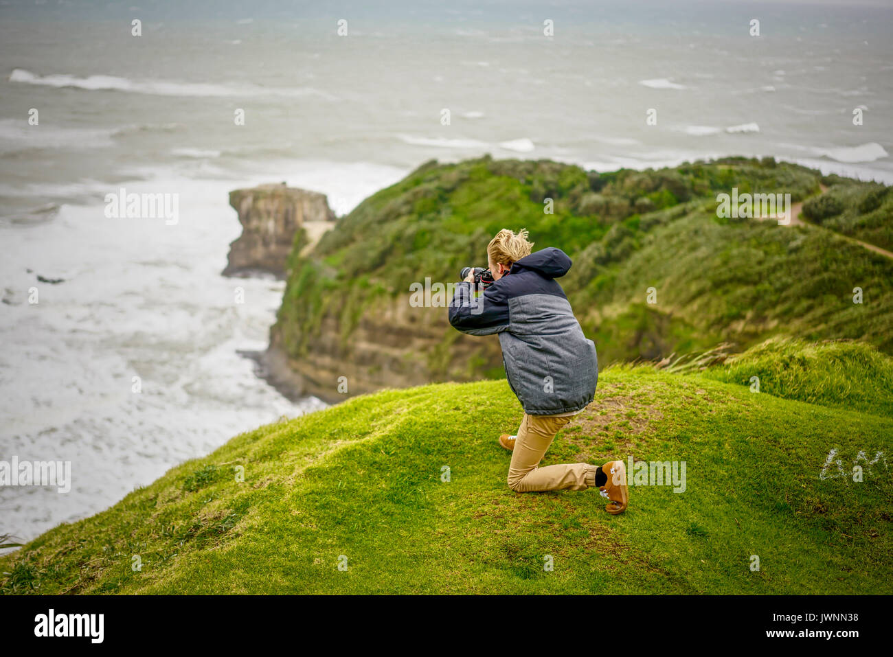 Photographer In Action At The Edge Of Cliff At Muriwai Beach, Auckland, New Zealand Stock Photo