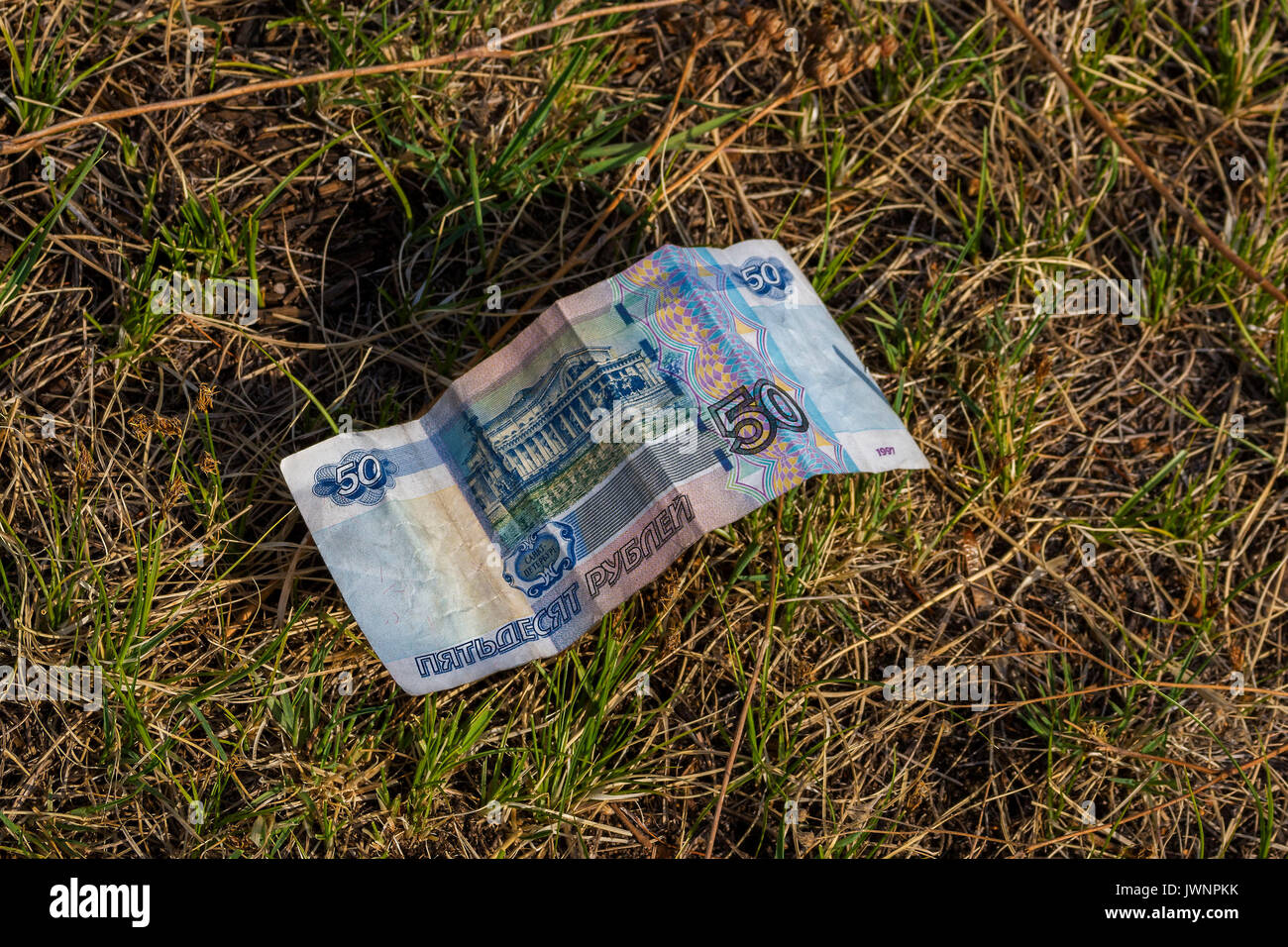 fifty rRussian monetary crumpled bill lying on the ground. Fifty rubles lying on the grass. Monetary lossoubles bill lie on the ground or grass . The  Stock Photo