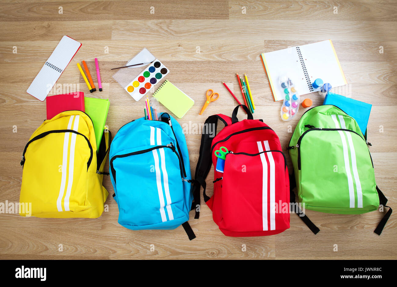 Colourful Children Schoolbags On Wooden Floor Stock Photo