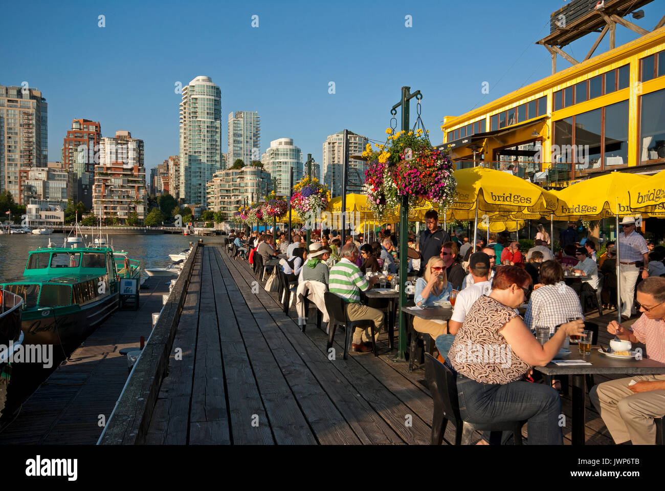 People dining on the terrace of the Bridges Restaurant, Granville Island, skyscrapers in the background, Vancouver, Canada Stock Photo