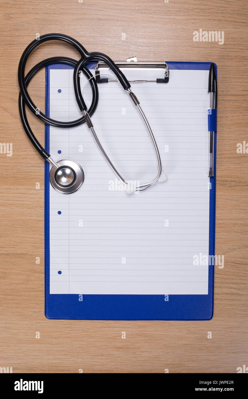 Stethoscope lying on a clipboard with blank paper on a wooden desk ...
