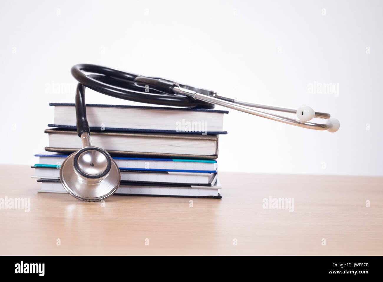 Acoustic stethoscope on pile of planners lying on desk Stock Photo