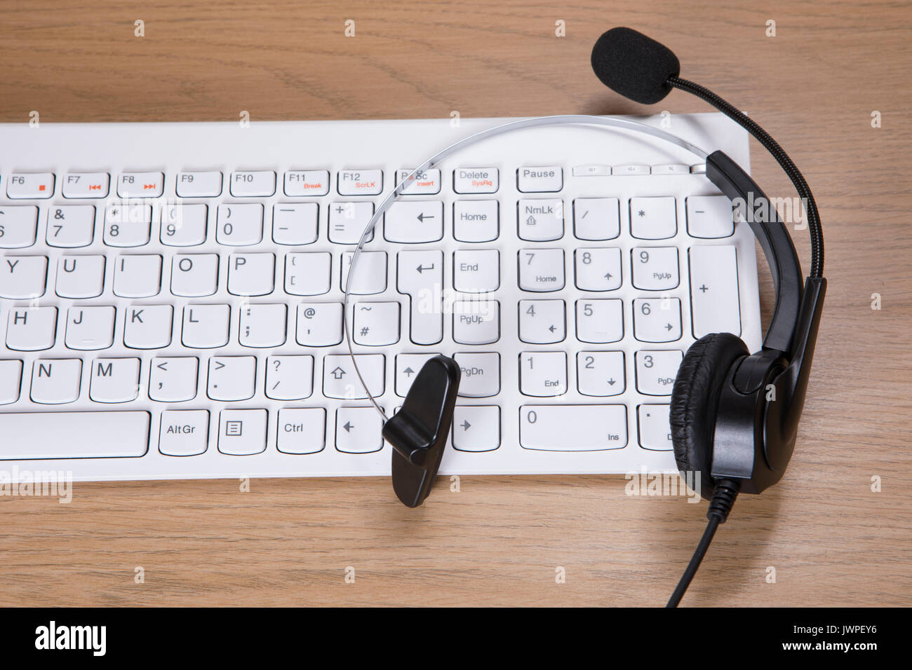 Telemarketing, call centre or client services concept with a headset with microphone on top of a white computer keyboard on a desk Stock Photo