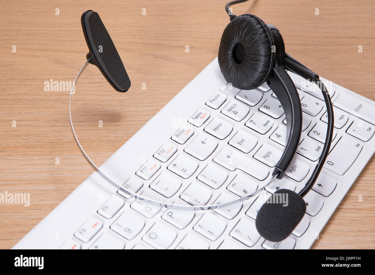 Headset with microphone lying on a white computer keyboard in a business communication and contact concept viewed close up from above Stock Photo