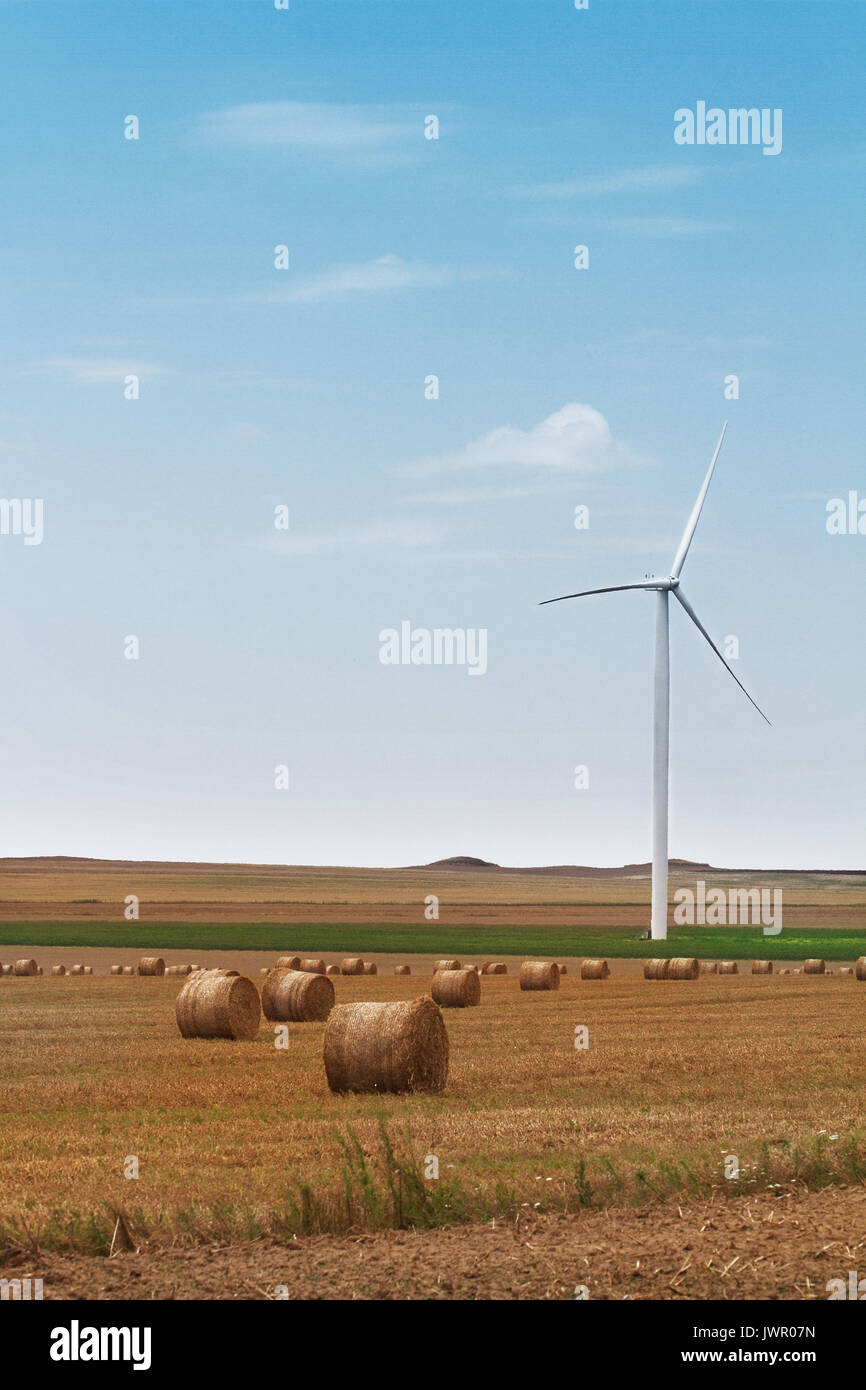 vertical view of eolian wind turbine on a meadow with wheat hay rolls on a  sunny day blue sky with clouds Stock Photo - Alamy