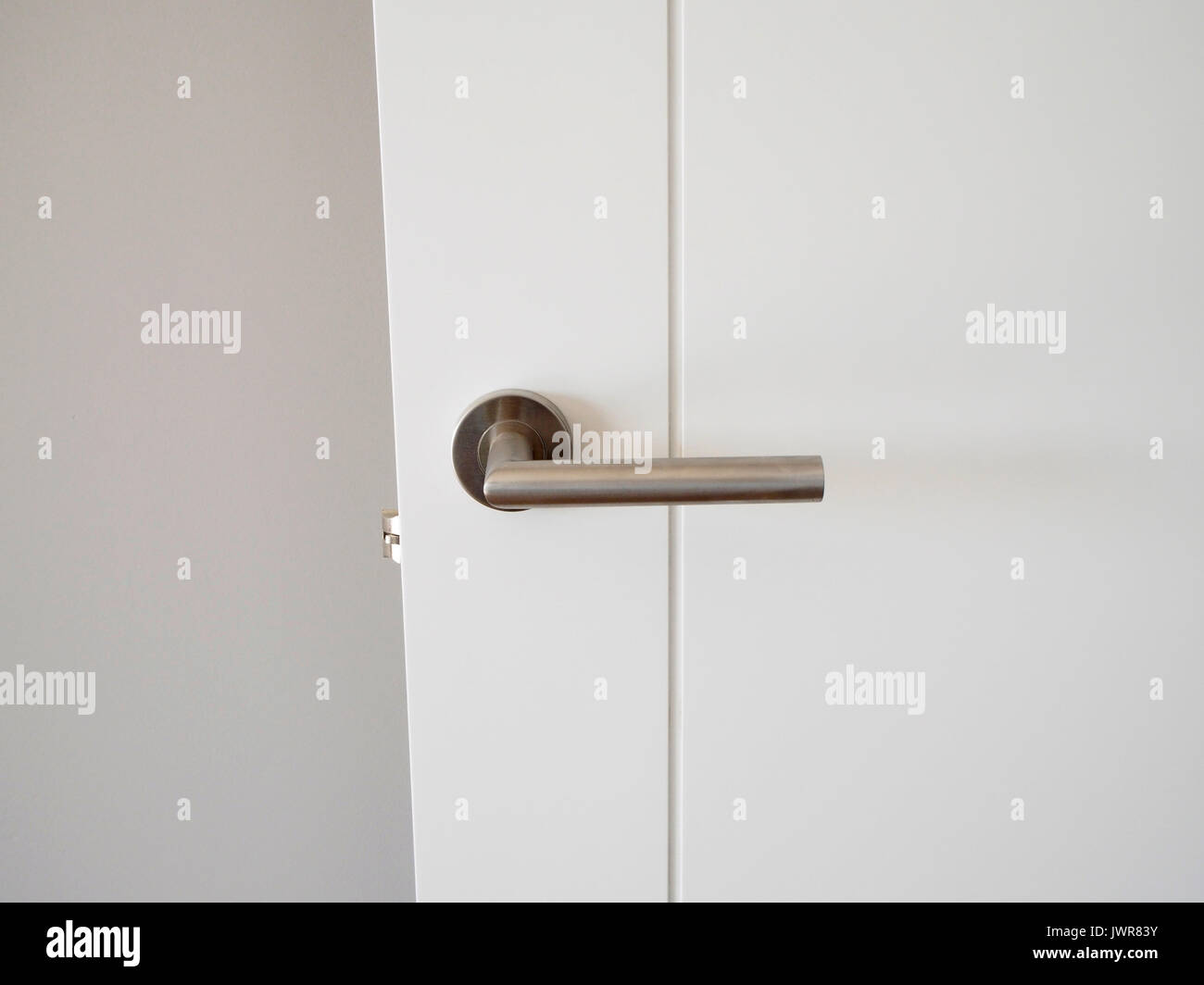 Metal handle in white door Stock Photo - Alamy