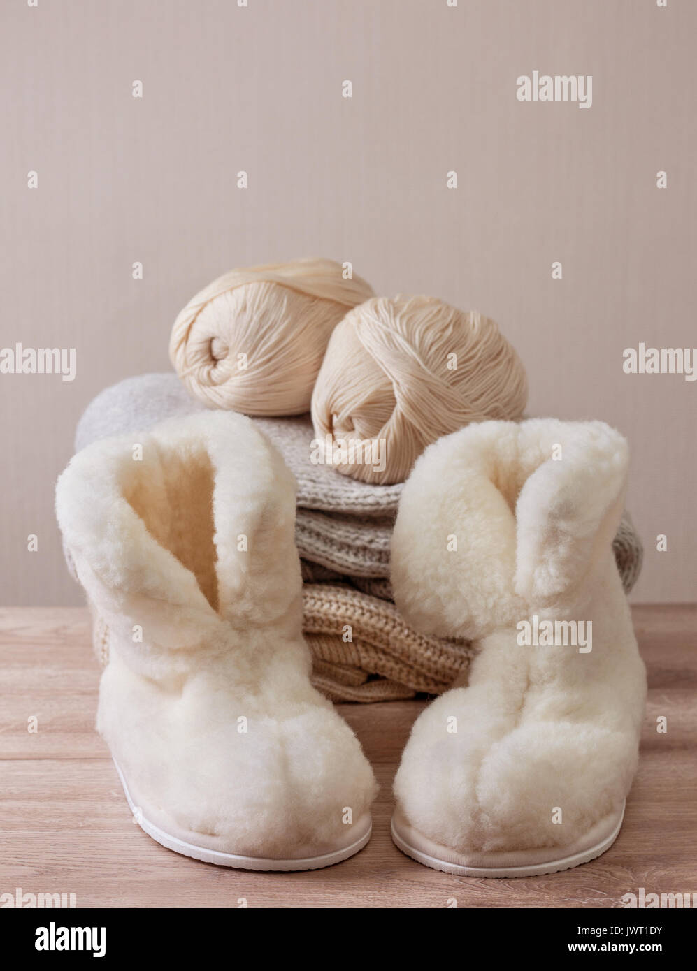 Pair of warm winter sheepskin slippers (alpaca), wool yarn  on a pile of warm woolen clothes (Selective focus) Stock Photo