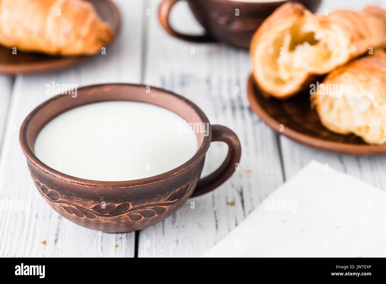 Cup of milk and fresh croissants on dark plate. White rustic table. Breakfast concept Stock Photo