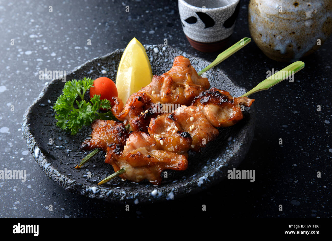 Japanese chicken grill or yakitori serve in izakaya style restourant set on Japanese style dish with flash lighting. Stock Photo