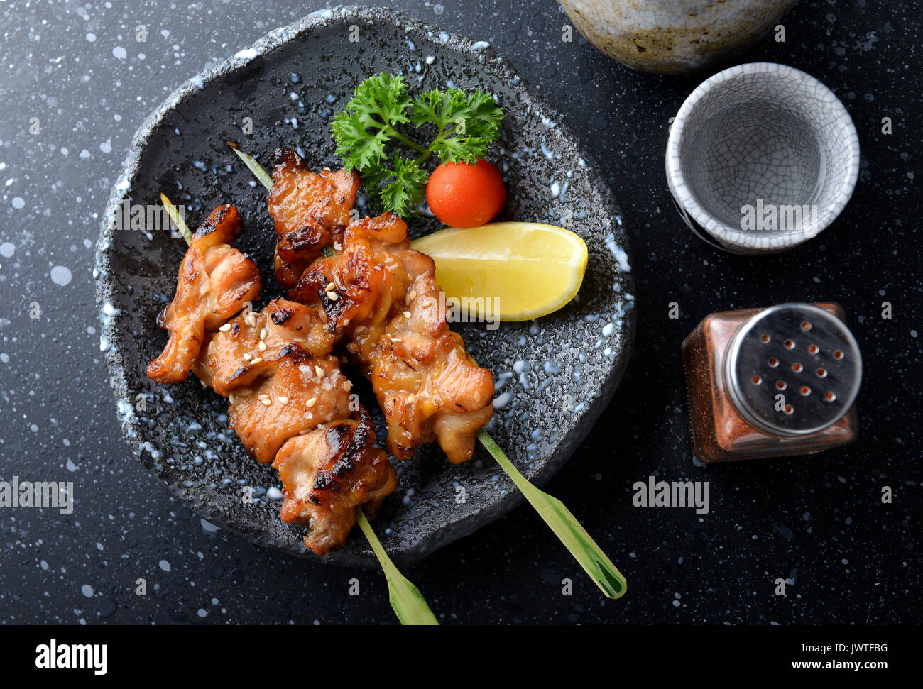 Japanese chicken grill or yakitori serve in izakaya style restourant set on Japanese style dish with flash lighting. Stock Photo