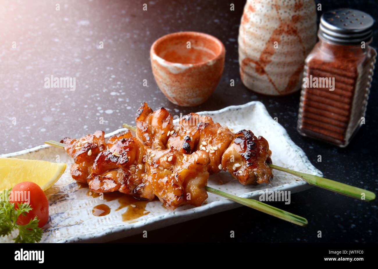 Japanese chicken grill or yakitori serve in izakaya style restourant set on Japanese style dish with flash lighting. Stock Photo