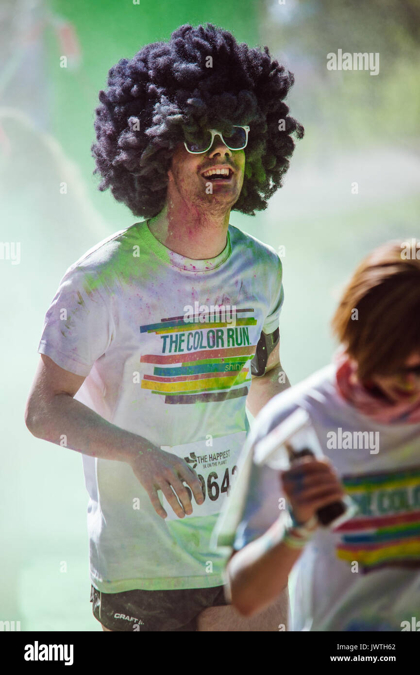 Happy man in an afro wig covered in paint and smoke during a Color Run Stock Photo