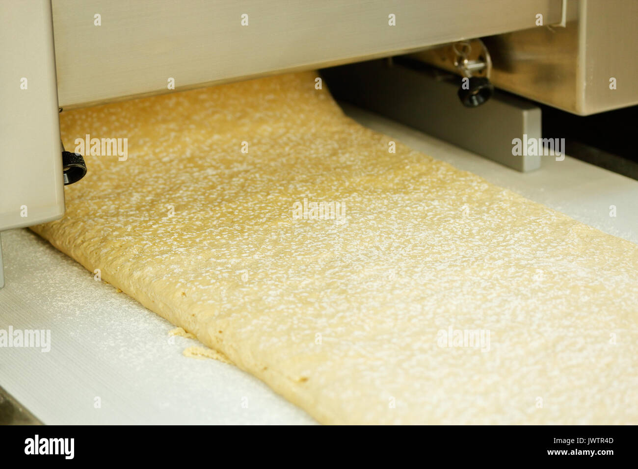 Dough sheeter machine produce continuous dough sheet. Selective focus. Stock Photo