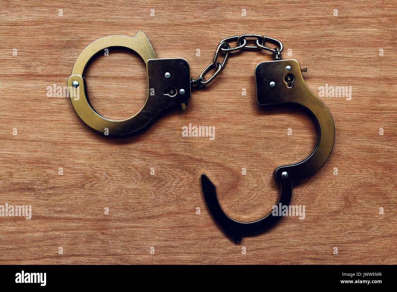 Handcuffs on wooden background, penitentiary and lock up concept Stock Photo