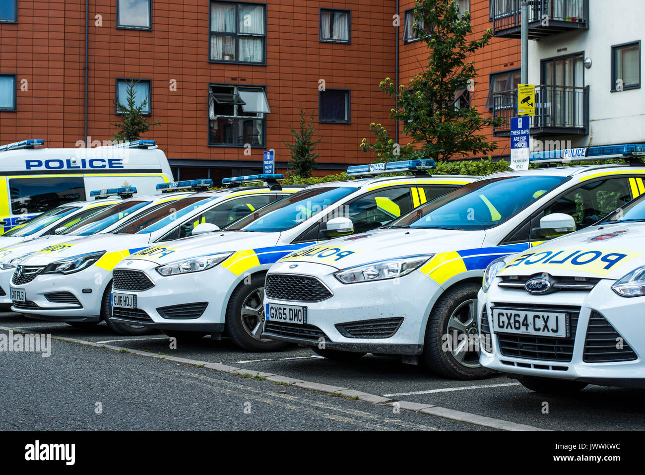 Parked British Police Cars In Front of a Modern Apartment Building Stock Photo