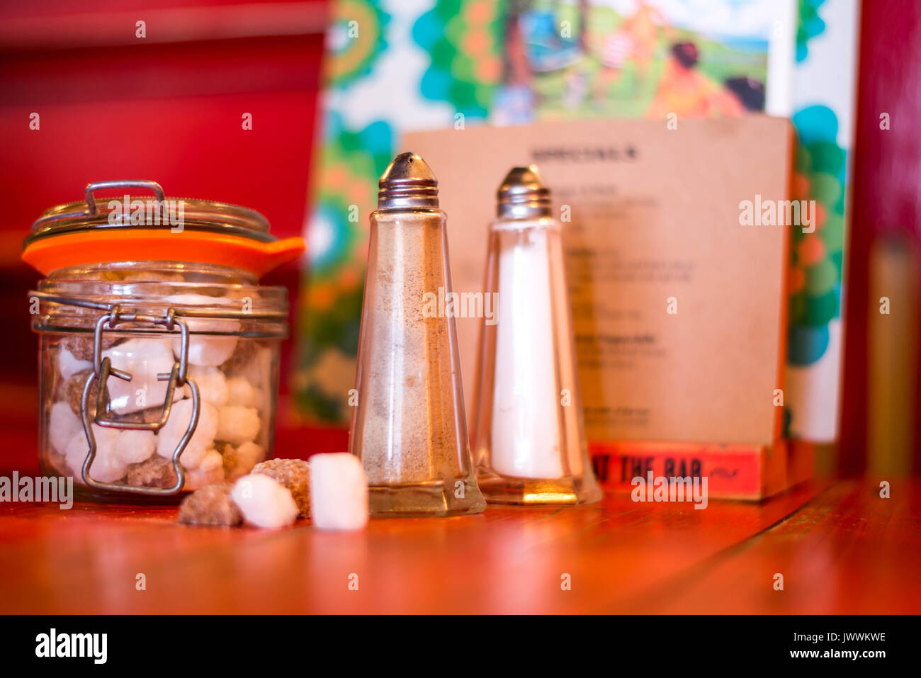Salt and Pepper Shakers on a Wooden Table Top With a Sugar Container or Pot Stock Photo