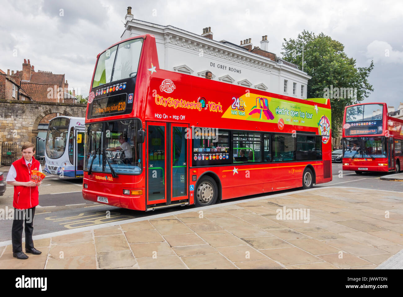 A bright red open topped hop-on hop-off double decker bus which takes tourists on a tour around the City of York Stock Photo