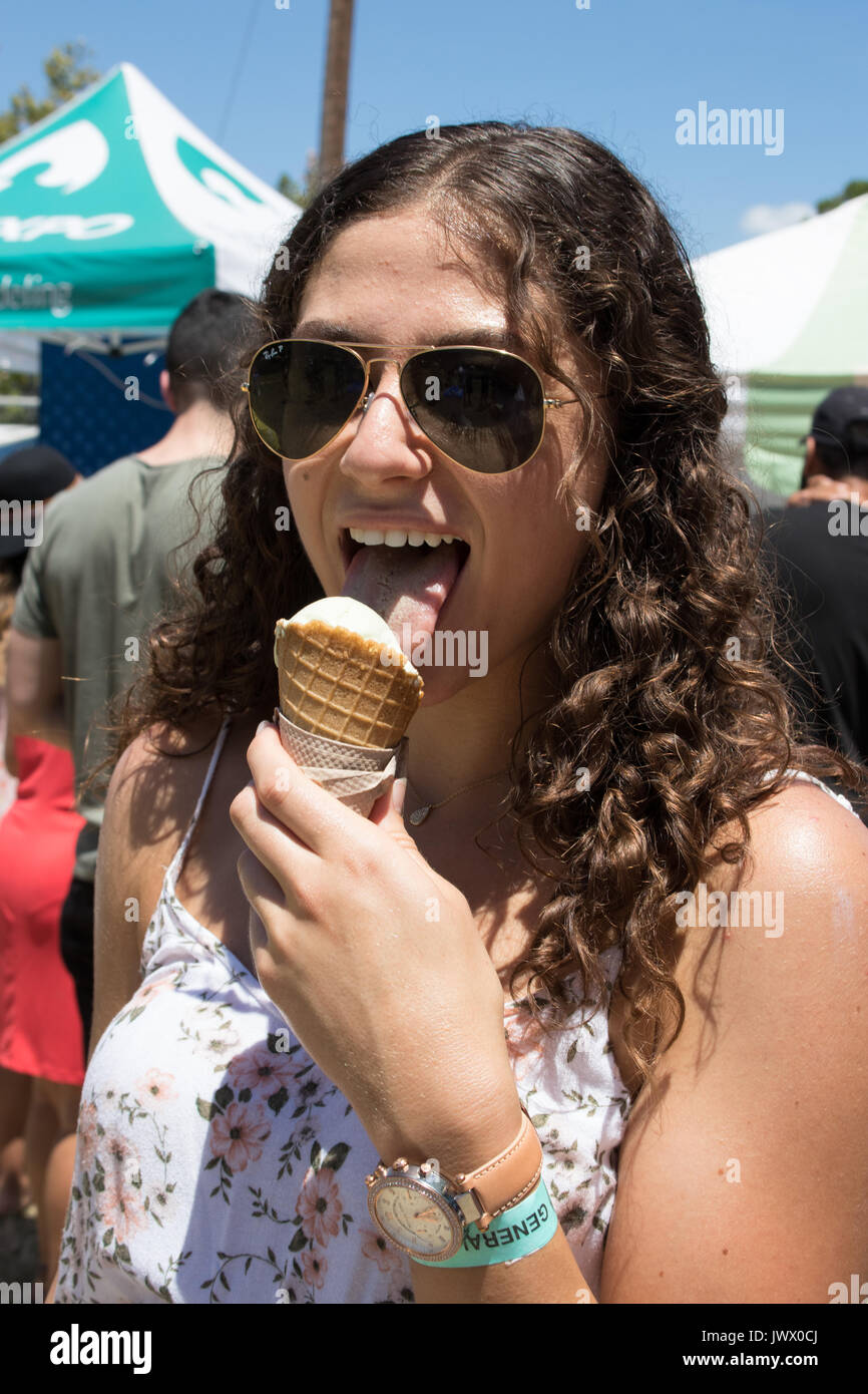Young woman with curly brown hair eating ice cream hires stock