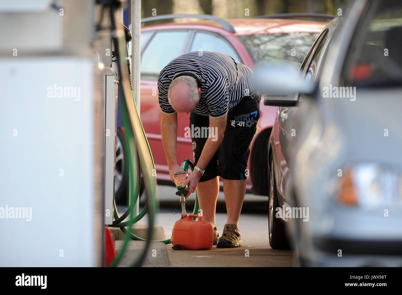 A man refills a small red jerrycan at a petrol station in Cardiff, Wales, UK. Stock Photo