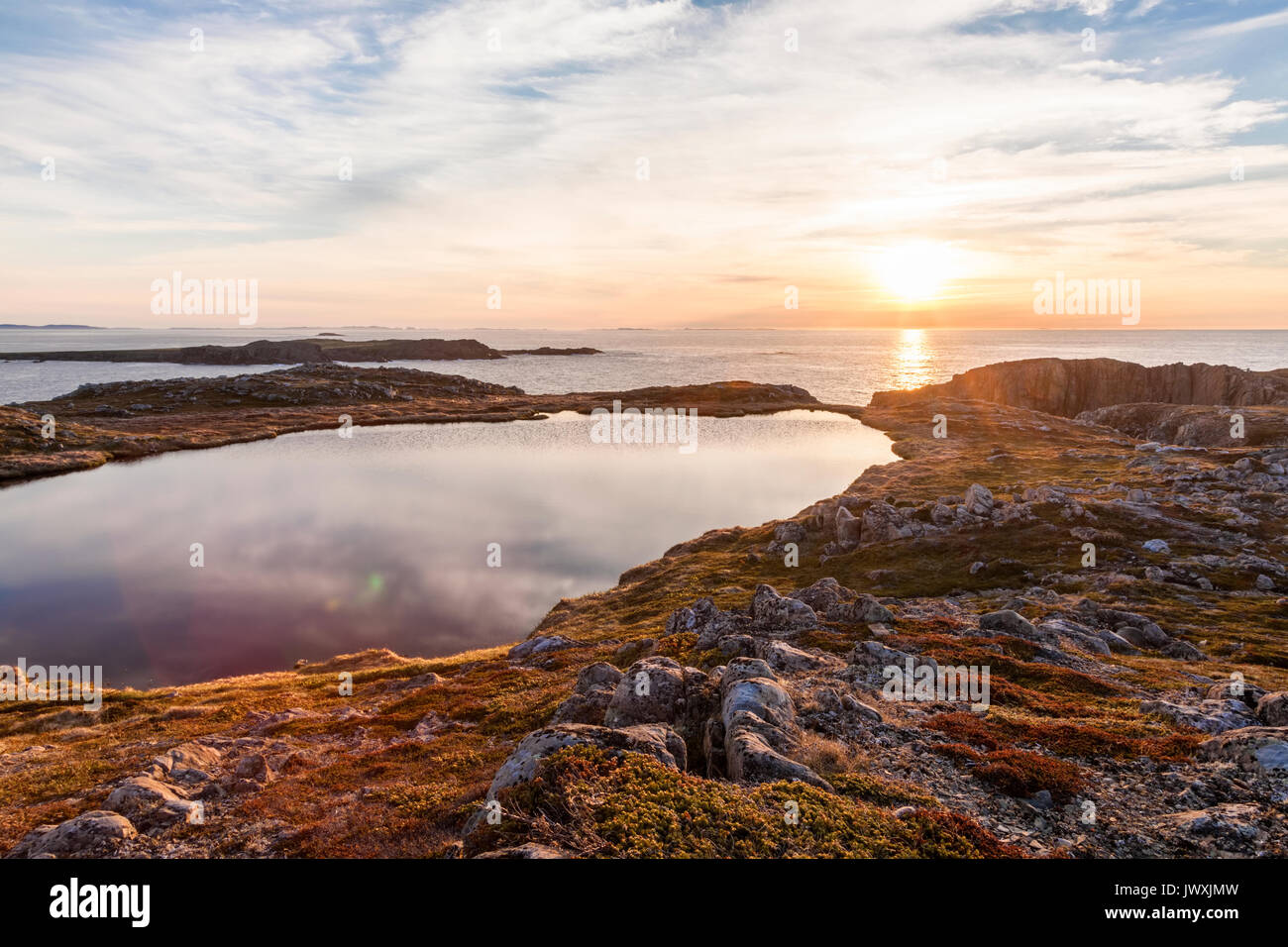A small lake barely separated from the Atlantic Ocean at sunset along the Bonavista Peninsula, Bonavista, Newfoundland and Labrador, Canada. Stock Photo