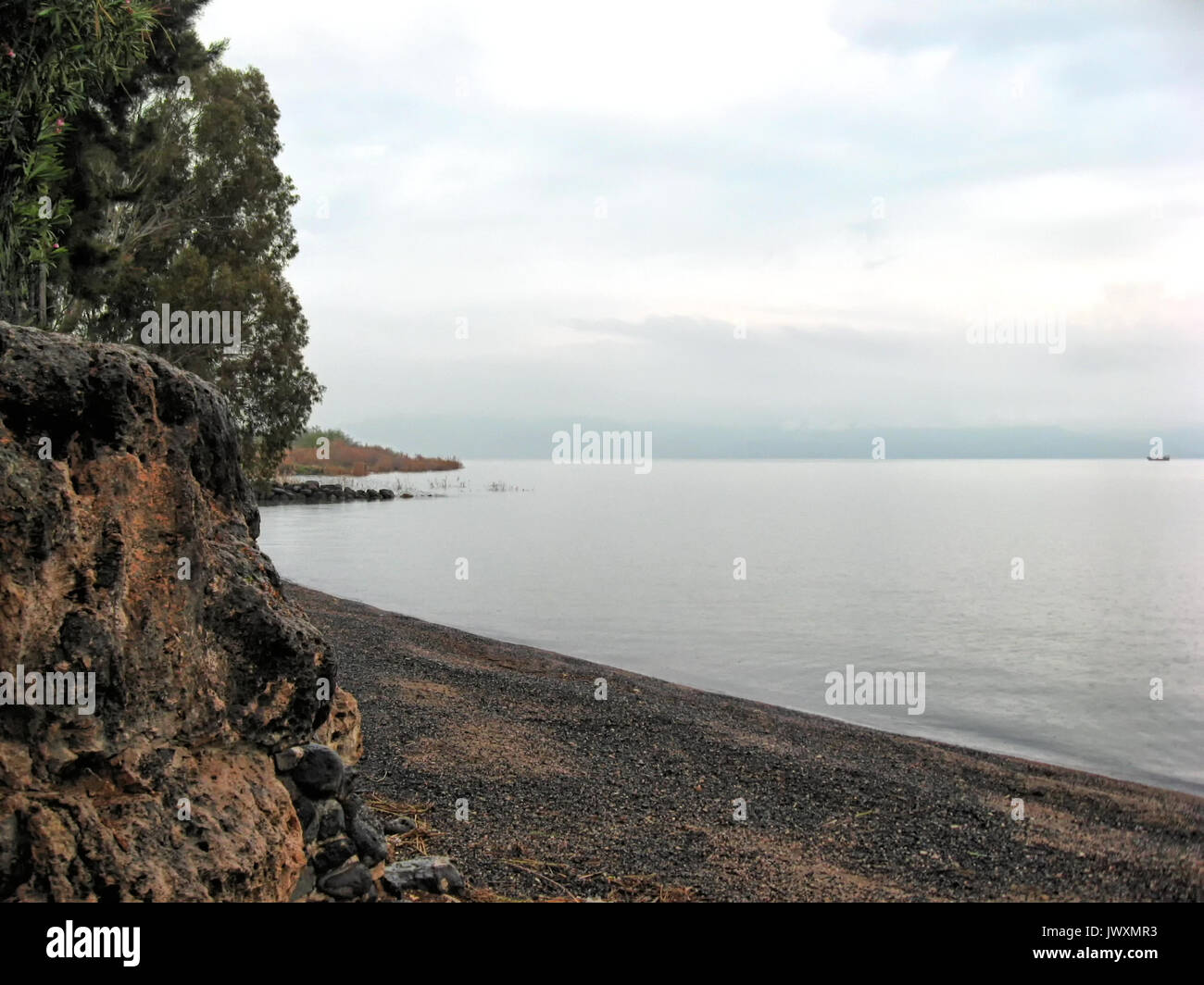 Dark basalt rock lines the western shore of the Sea of Galilee at Tabgha in Israel. Stock Photo