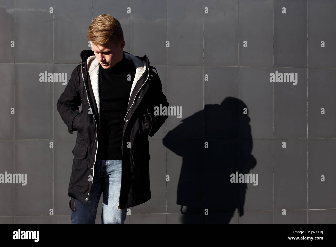 Young stylish redhead man in trendy outfit posing against urban background Stock Photo