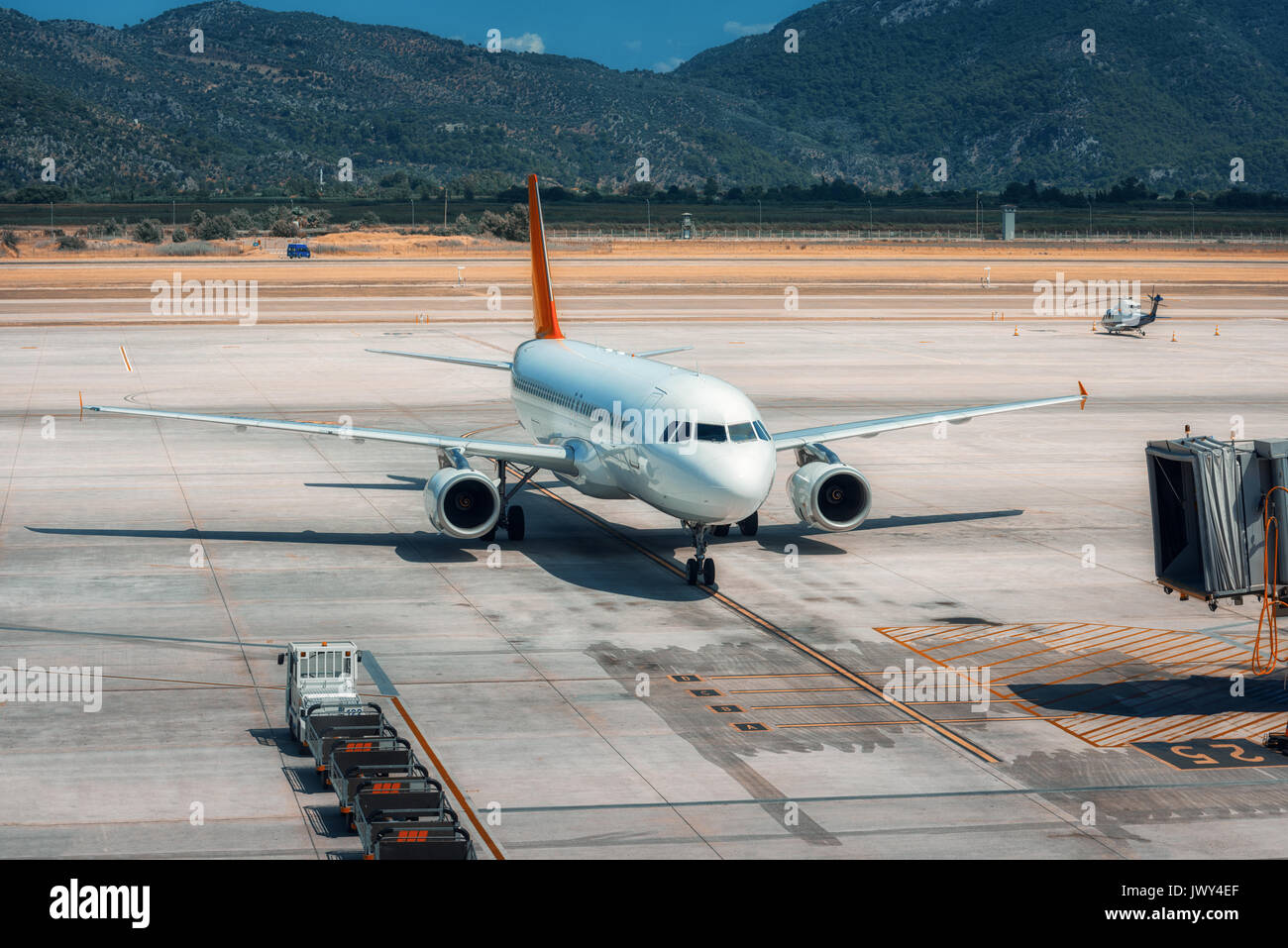 Beautiful white airplane on the runway in Dalaman airport. Landscape with big passenger airplane is taking off and mountains at bright sunny day Stock Photo