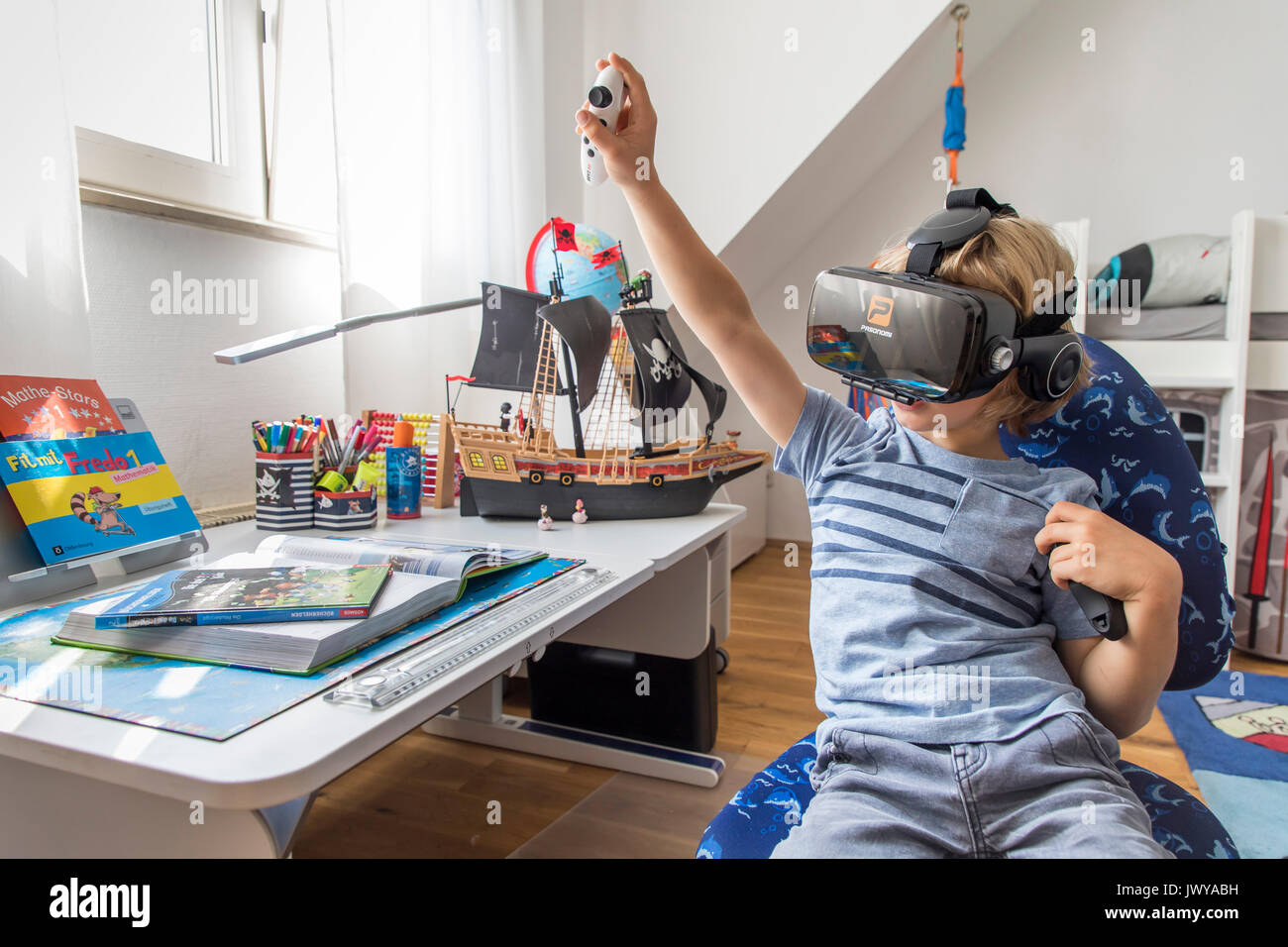Little boy, 7 years old, plays a 3-D computer game, with a virtual reality headset, in his children's room, Stock Photo
