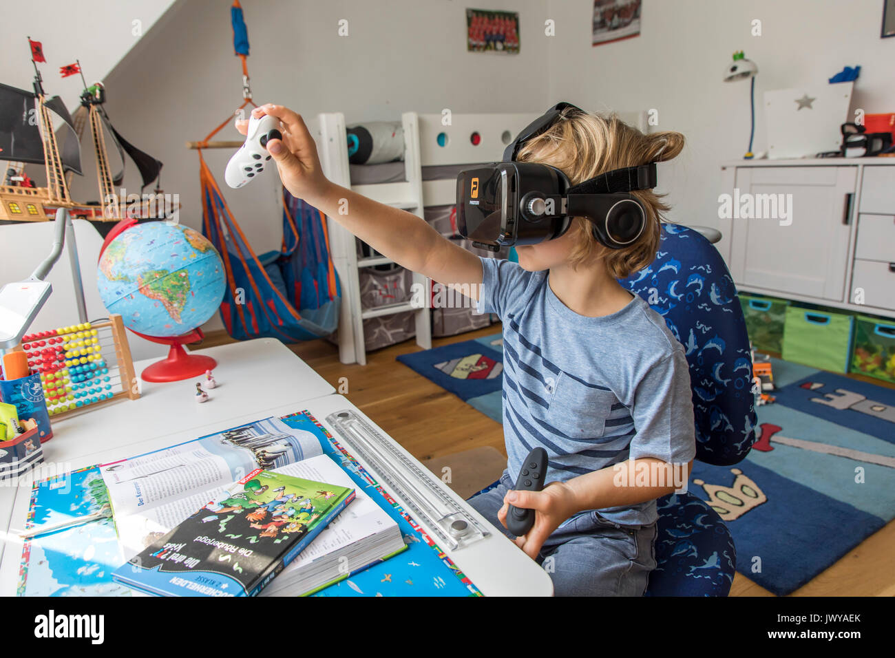 Little boy, 7 years old, plays a 3-D computer game, with a virtual reality headset, in his children's room, Stock Photo