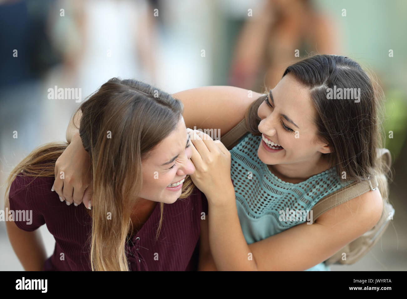 Two happy friends meeting and joking laughing on the street Stock Photo