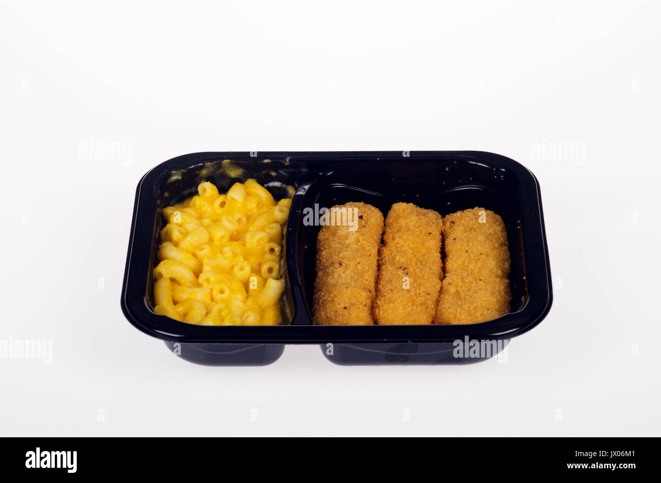 Cooked mac and cheese with chicken fingers ready meal in plastic tray on white background cut out, USA Stock Photo