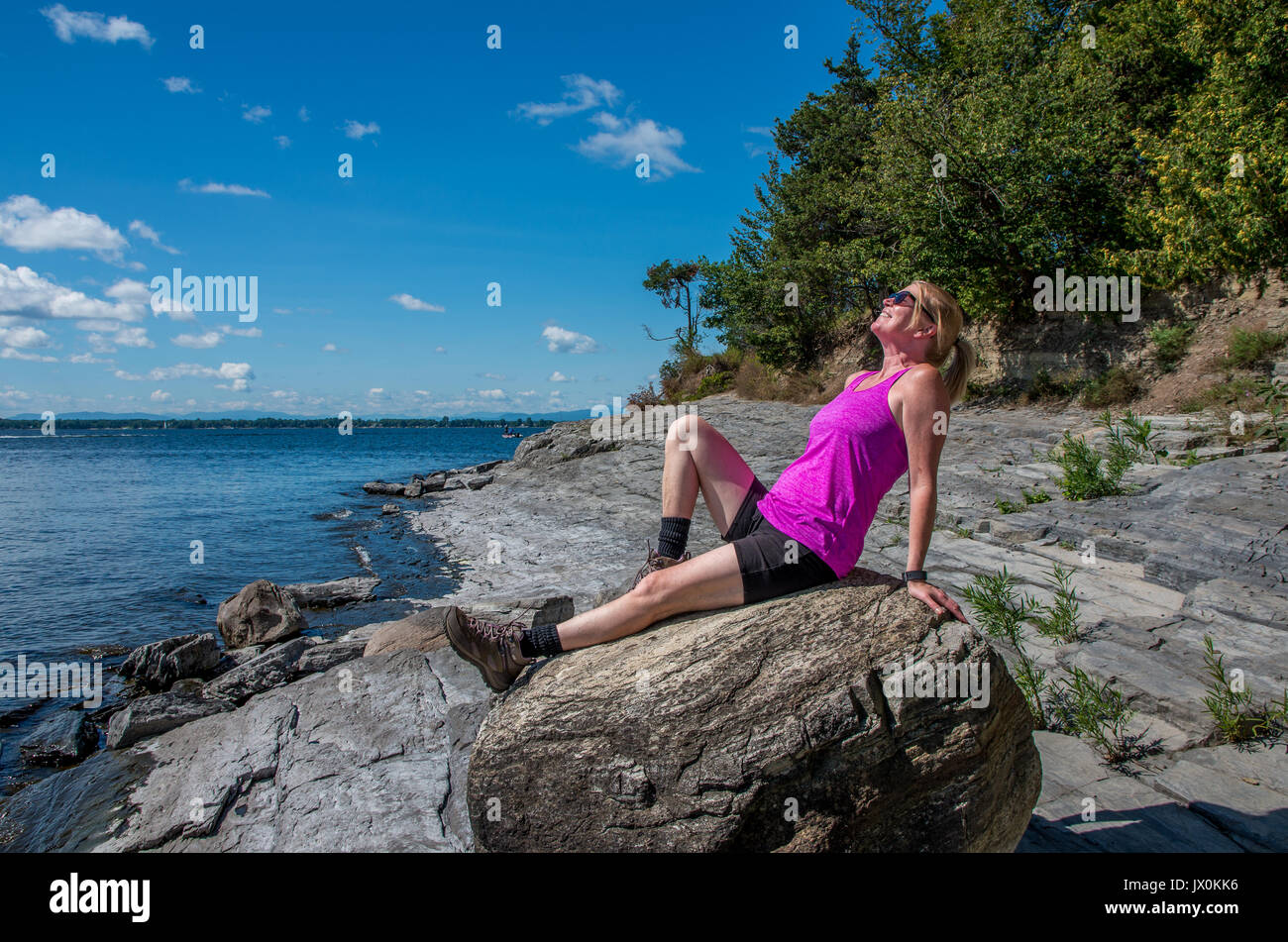 on a rocky shore of lake Champlain walking and looking out onto the lake Stock Photo