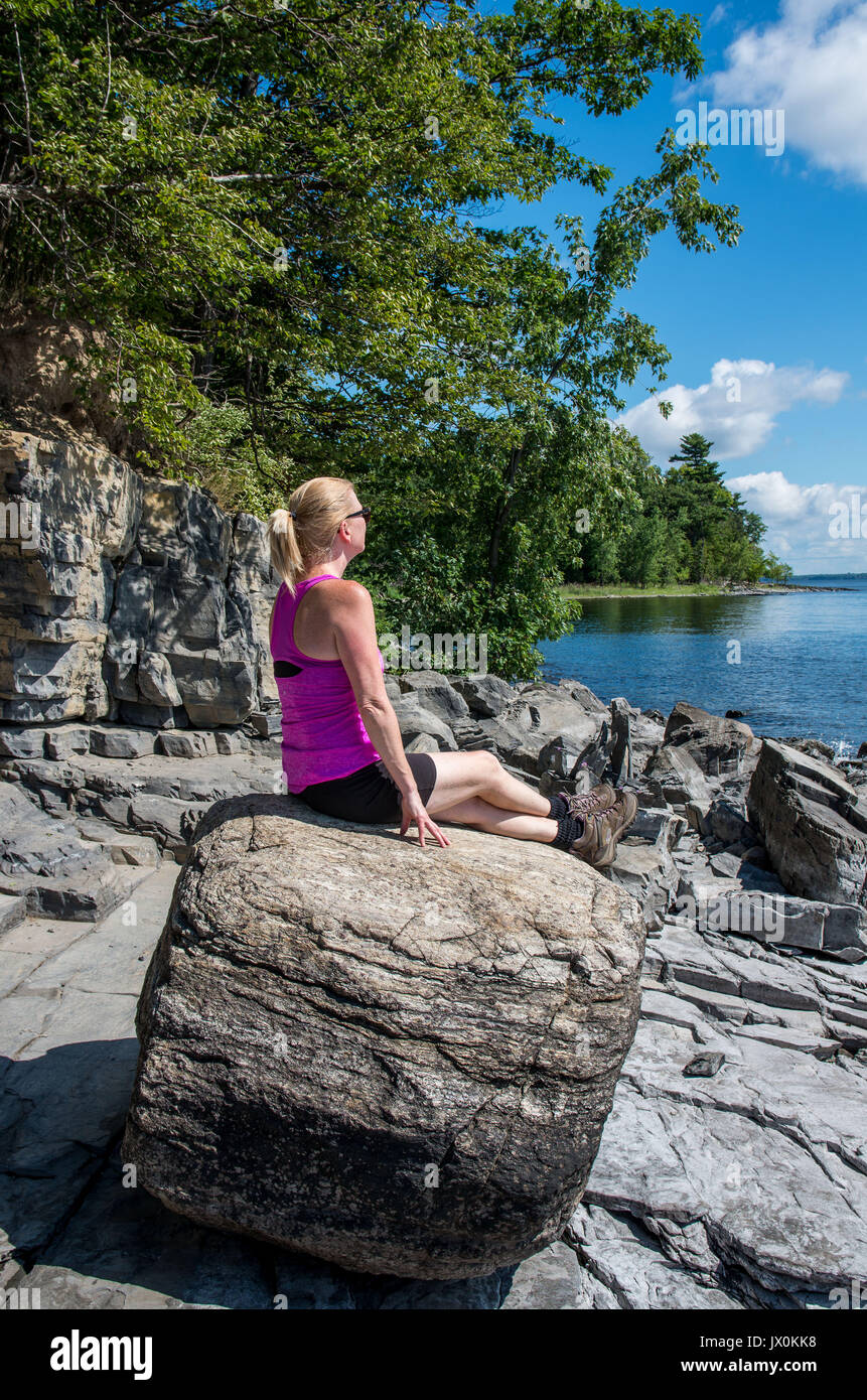 on a rocky shore of lake Champlain walking and looking out onto the lake Stock Photo