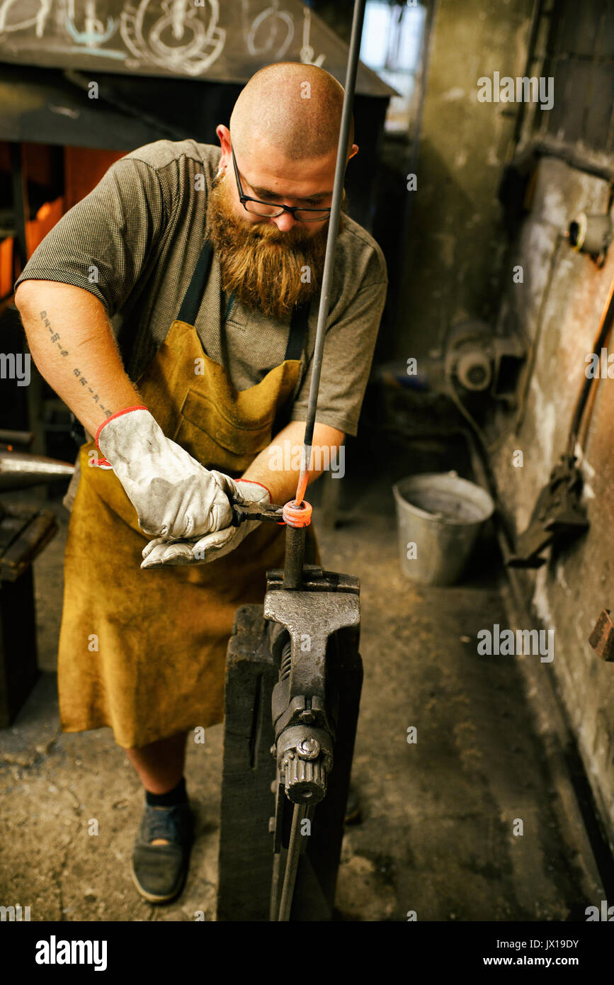 Blacksmith with beard working in his workshop Stock Photo