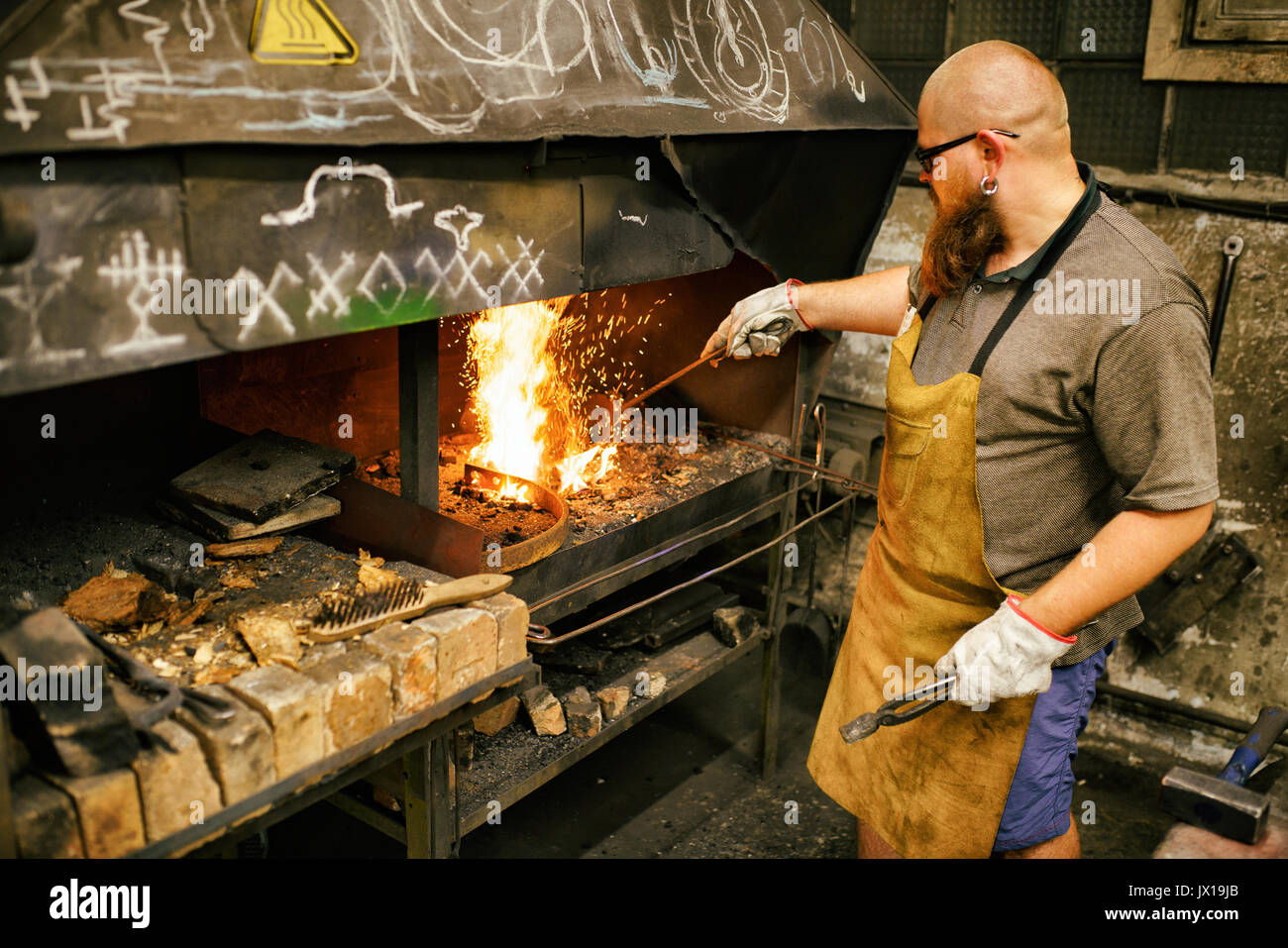 Blacksmith with beard working in his workshop Stock Photo