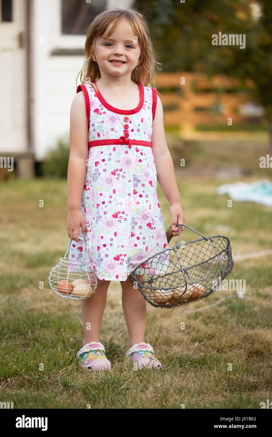 Little girl helping colect free range eggs with her egg basket. Stock Photo
