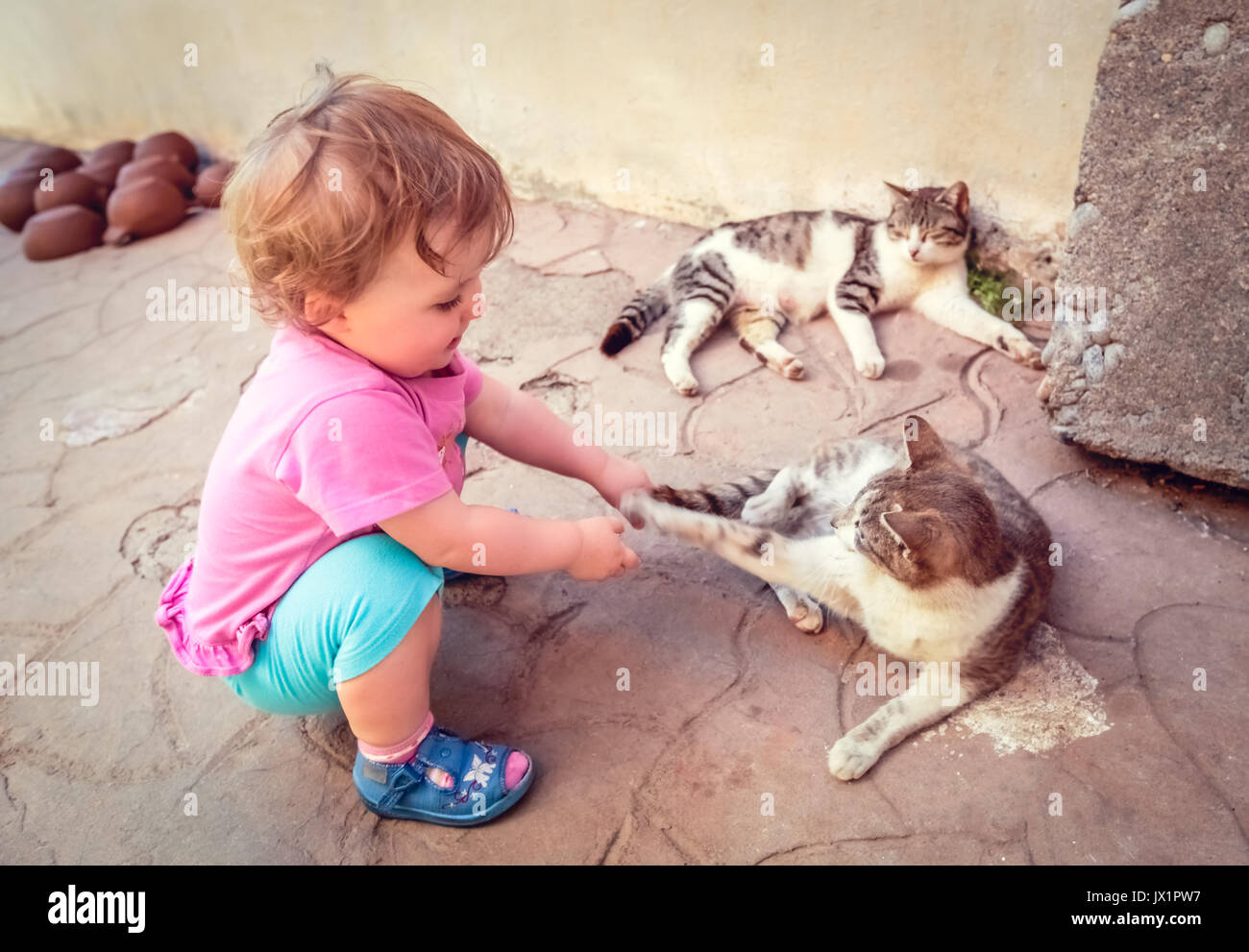 Happy little caucasian girl playing with two lazy cats Stock Photo Alamy