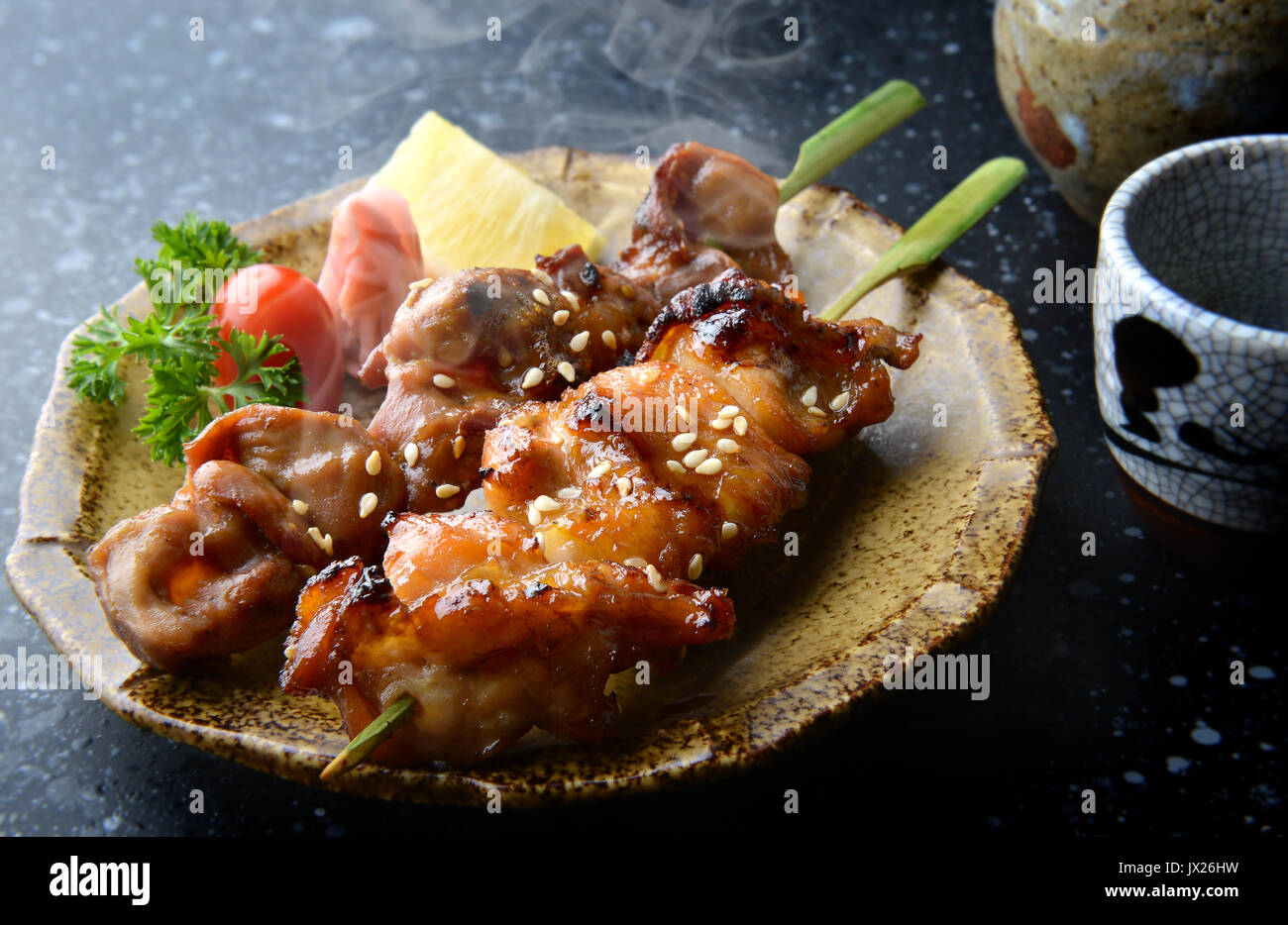 Japanese chicken grill or yakitori serve in izakaya style restourant set on Japanese style dish with flash lighting. Stock Photo