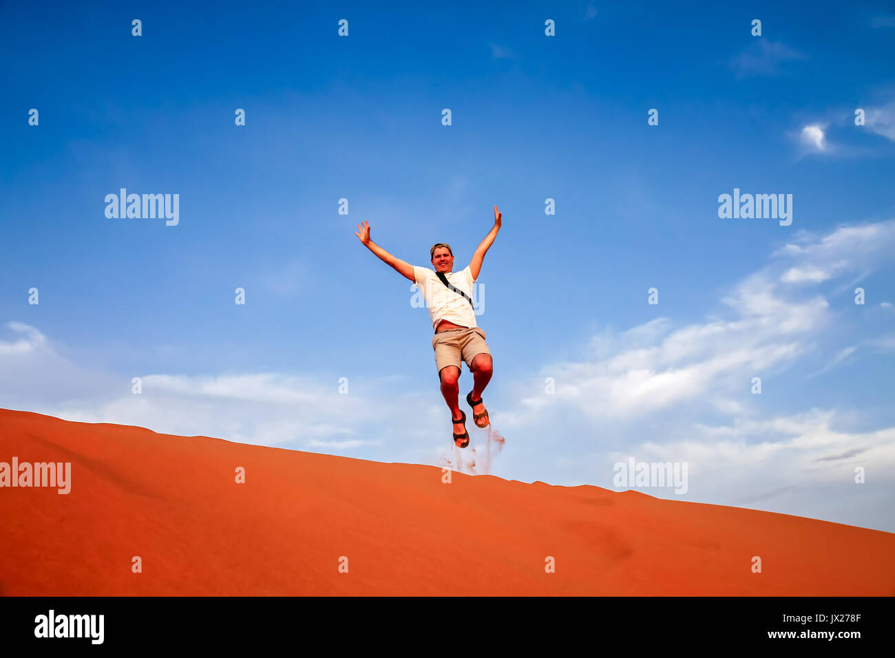 Tourist jumping in the air at the stunning sand dunes of Sahara desert ...