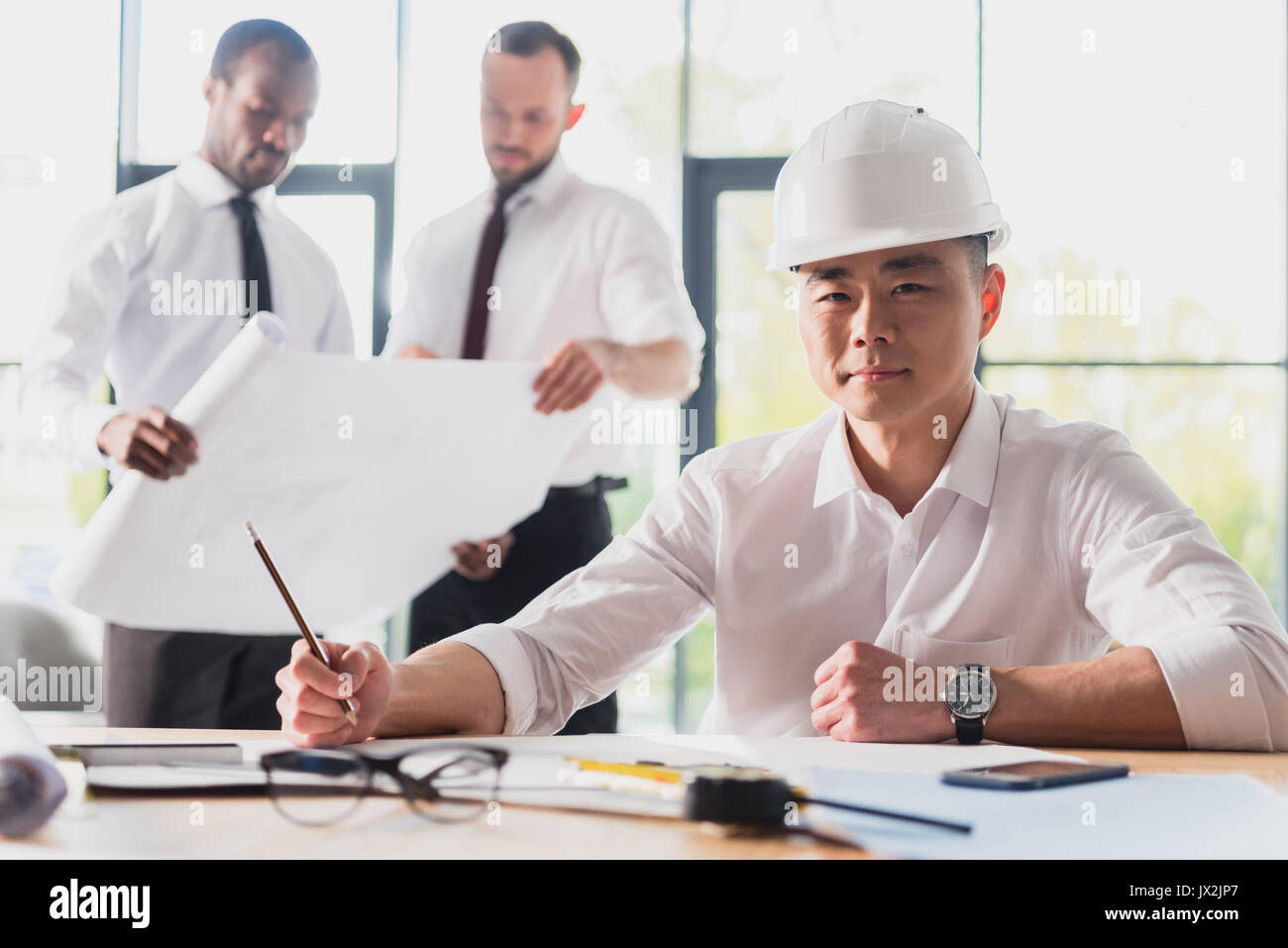 architect working on new project with colleagues behind in modern office Stock Photo