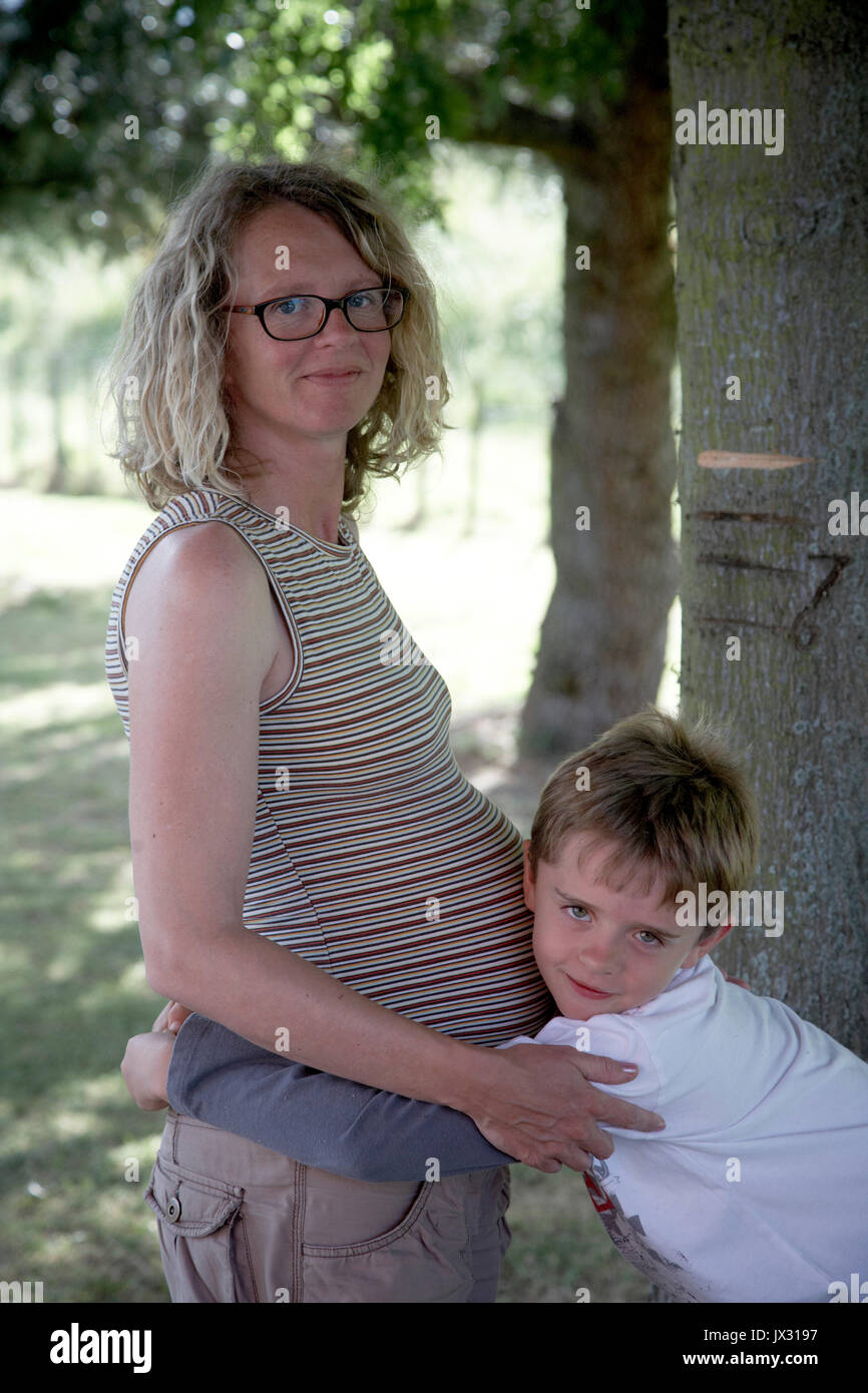Elder brother with pregnant mum hugging bump Stock Photo