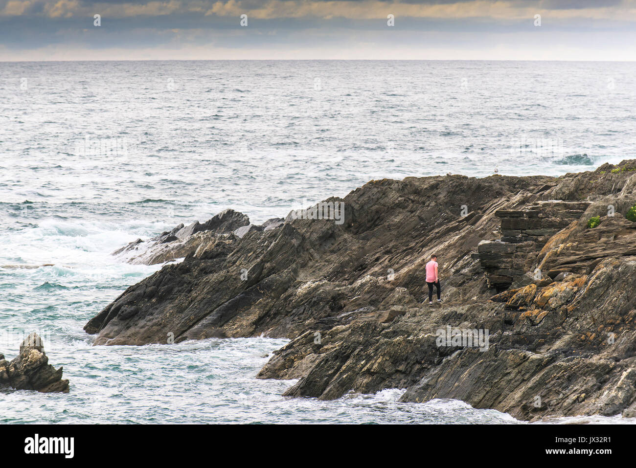 A man walking on rocks on the North Cornwall coast. Stock Photo