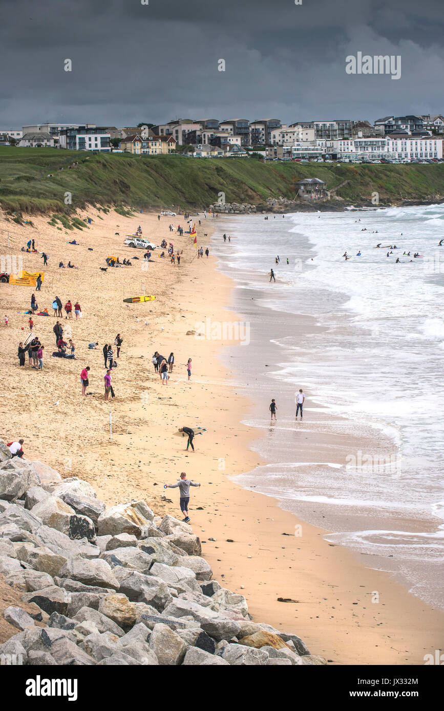 UK Weather. Holidaymakers enjoying themselves on Fistral Beach despite dark clouds gathering. Stock Photo