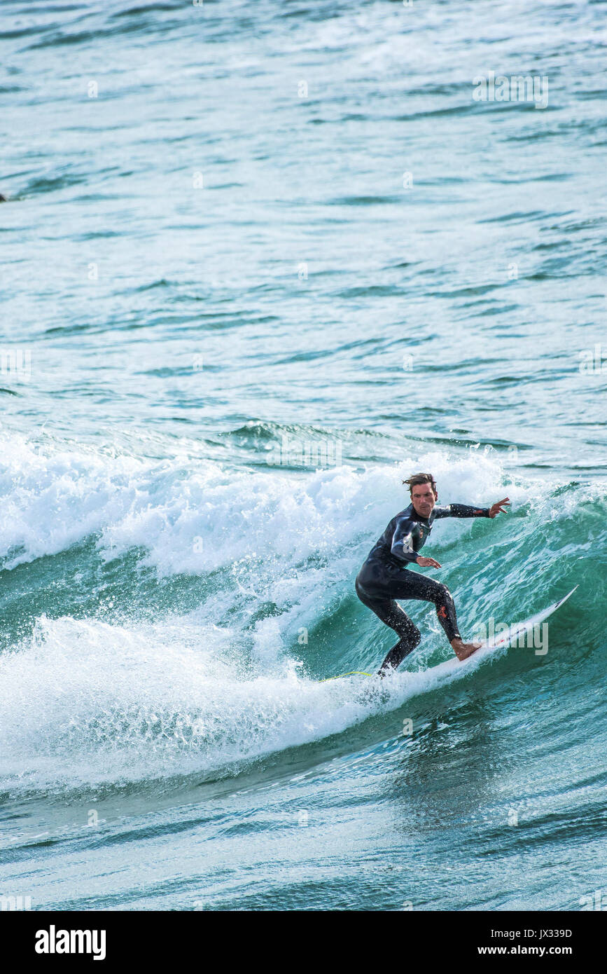 Surfing UK. A surfer riding a wave at Fistral in Newquay, Cornwall
