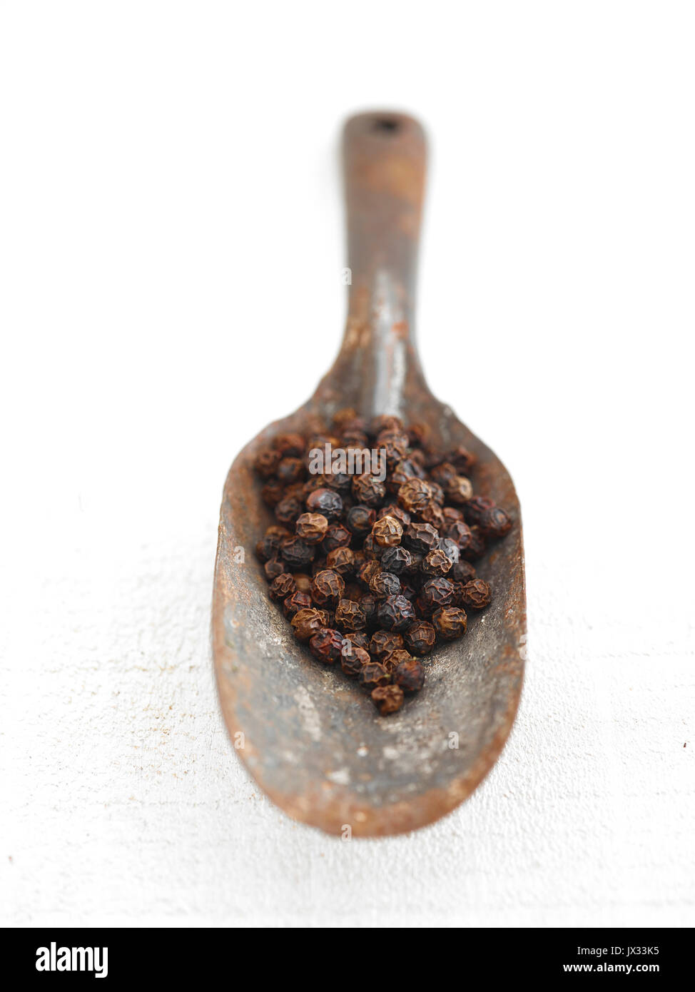 whole black peppercorns and rustic spoon Stock Photo