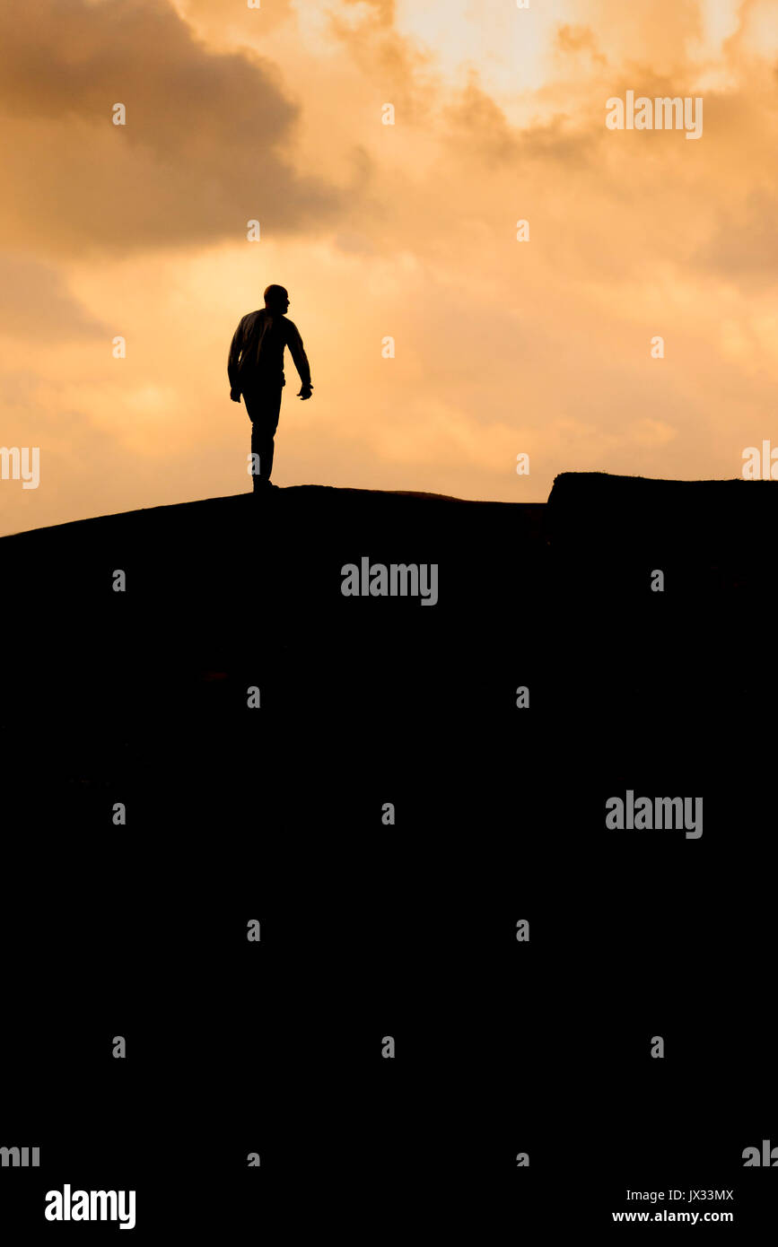 The silhouette of a man walking at sunset Stock Photo - Alamy